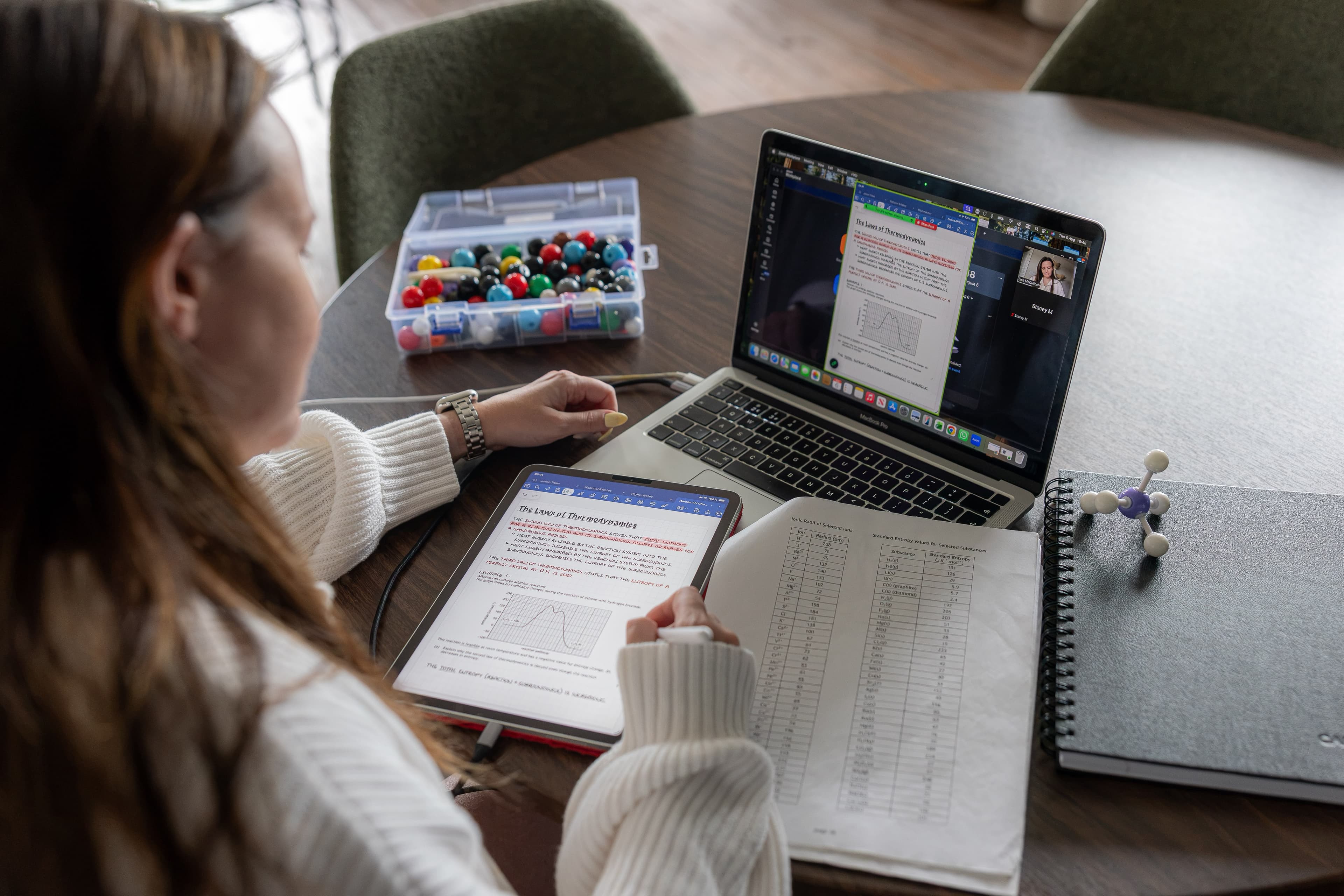 A student on a video call, studying with notes and a laptop